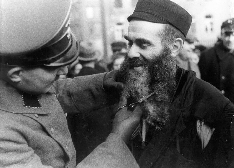 A German soldier cuts a Jews beard in the ghetto